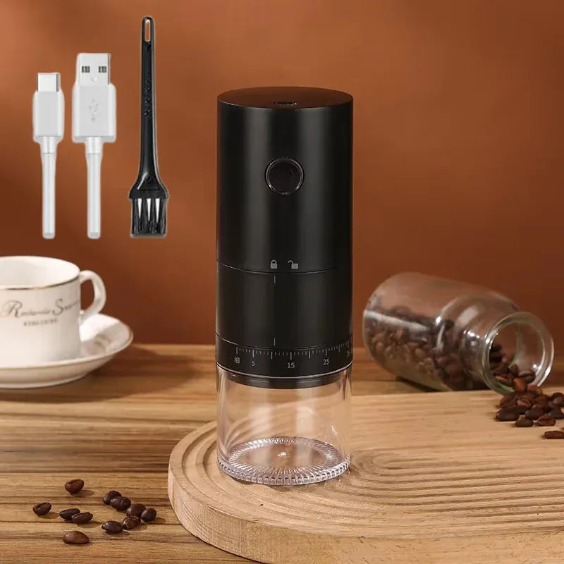 Black coffee grinder on a wooden surface with coffee beans and a cup in the background.