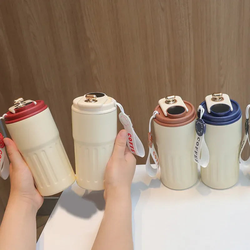 Set of colorful coffee cups with handles held by a hand against a wooden background