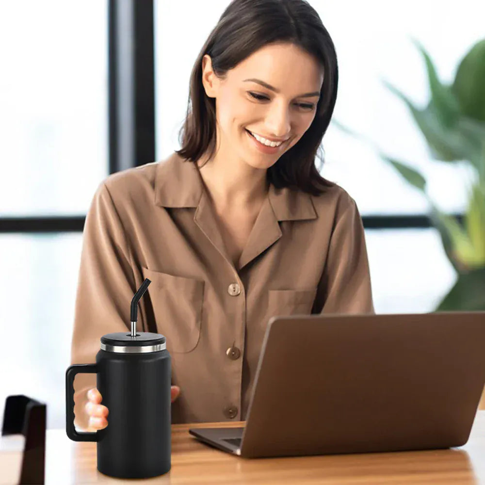 Woman sitting at a desk with a laptop and black mug, smiling.