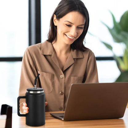 Woman sitting at a desk with a laptop and black mug, smiling.