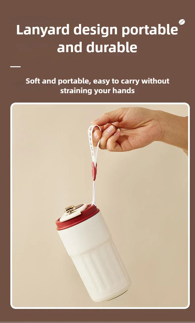 White tumbler with red lid held by a hand with a lanyard, on a beige background.