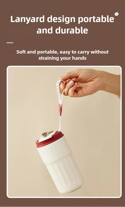 White tumbler with red lid held by a hand with a lanyard, on a beige background.