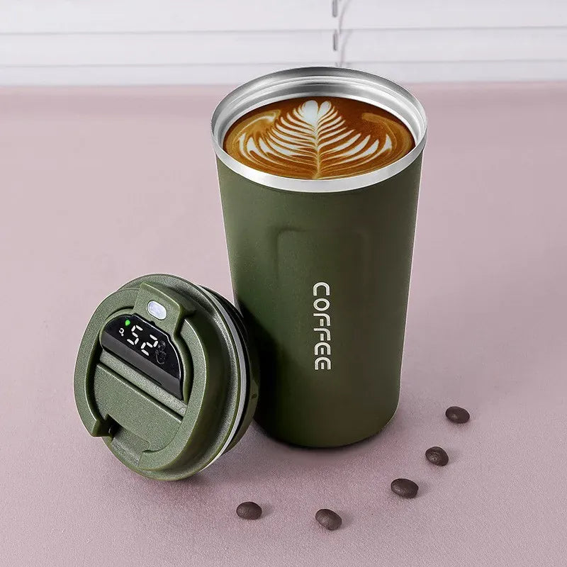 Green insulated coffee tumbler with a lid on a pink surface, filled with a hot beverage.