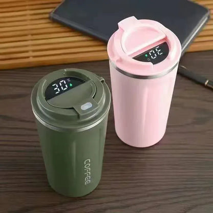 Two insulated travel mugs, one green and one pink, with digital temperature displays on a wooden surface.