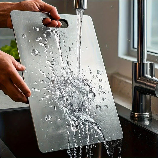 Person washing a cutting board under running water in a kitchen.
