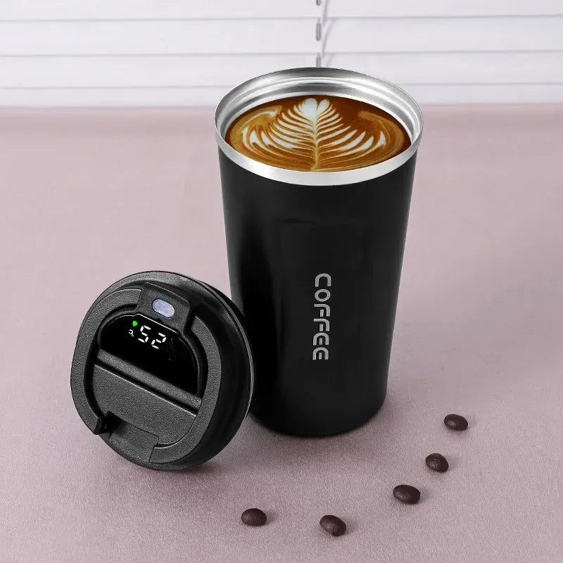 Black insulated coffee tumbler with a digital temperature display on a pink surface with coffee beans.
