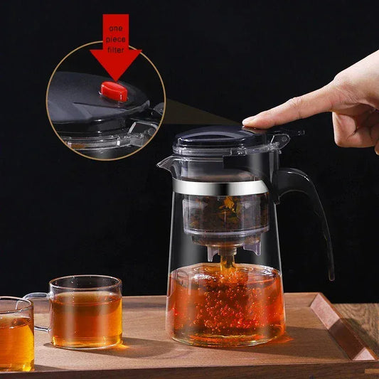 Tea-making setup with a glass teapot and cups on a wooden surface, featuring a close-up of the tea filter.