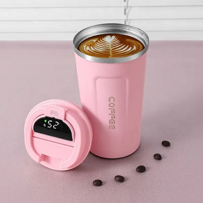 Pink insulated coffee tumbler with a digital temperature display on a pink surface with coffee beans.
