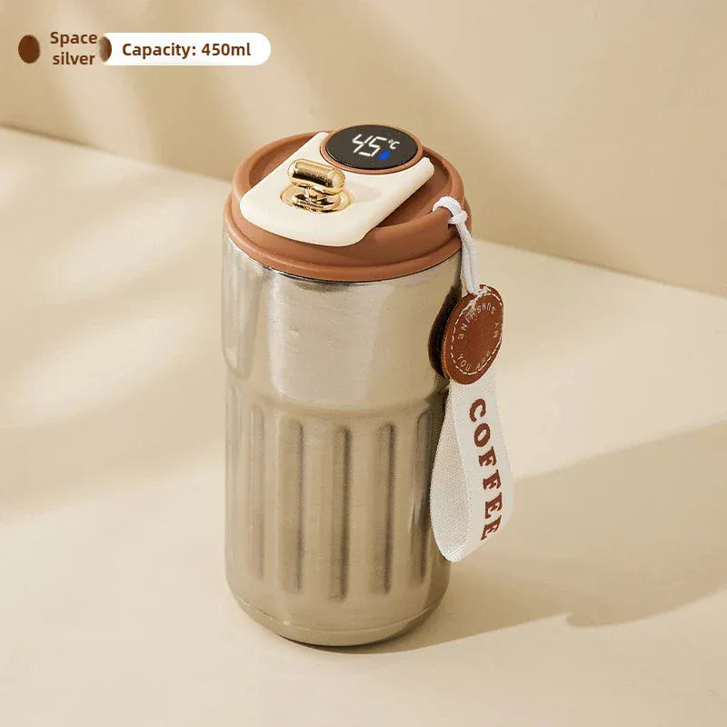 Stainless steel coffee tumbler with brown lid and digital temperature display on a beige background