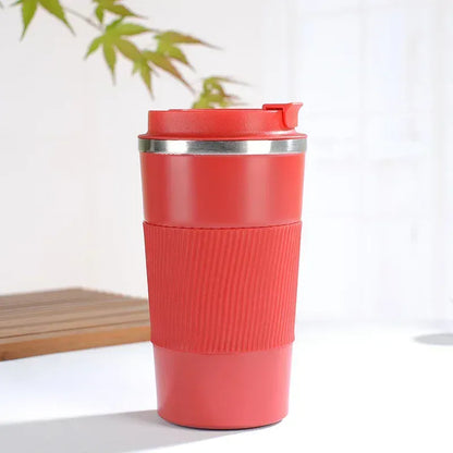 Red travel mug with a silver lid on a white surface with a plant in the background