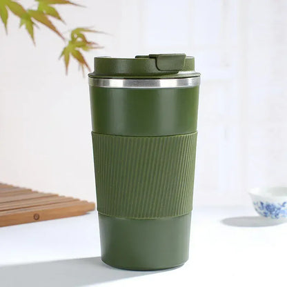 Green insulated travel mug on a white surface with a blurred background
