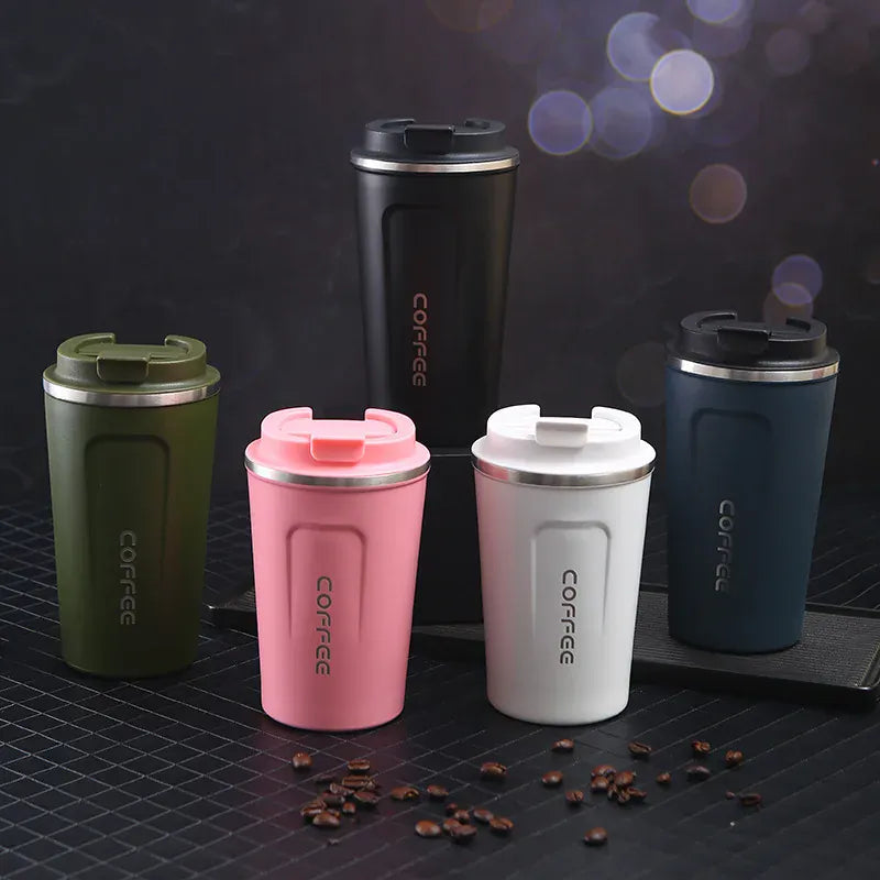 Set of four colorful coffee tumblers with 'COFFEE' text on a dark surface with scattered coffee beans.