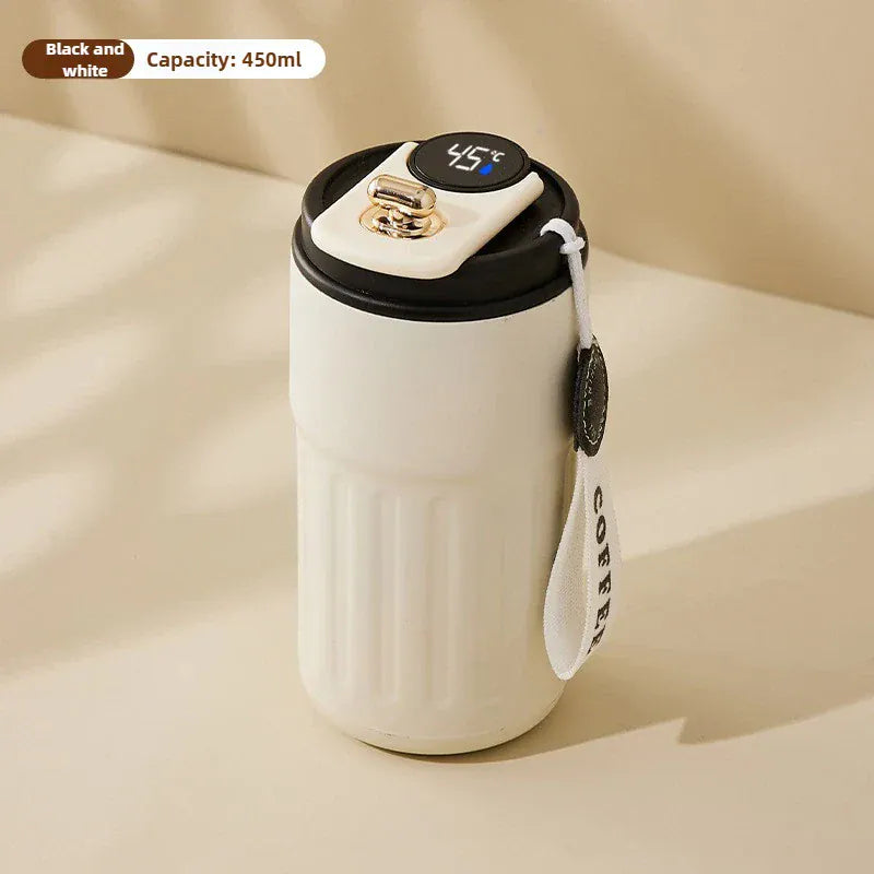 White ceramic mug with black lid and handle on a beige background