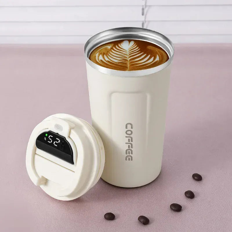 White insulated coffee tumbler with a digital temperature display on a pink surface.