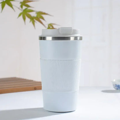 Light blue travel mug with a silver lid on a white surface with a blurred background