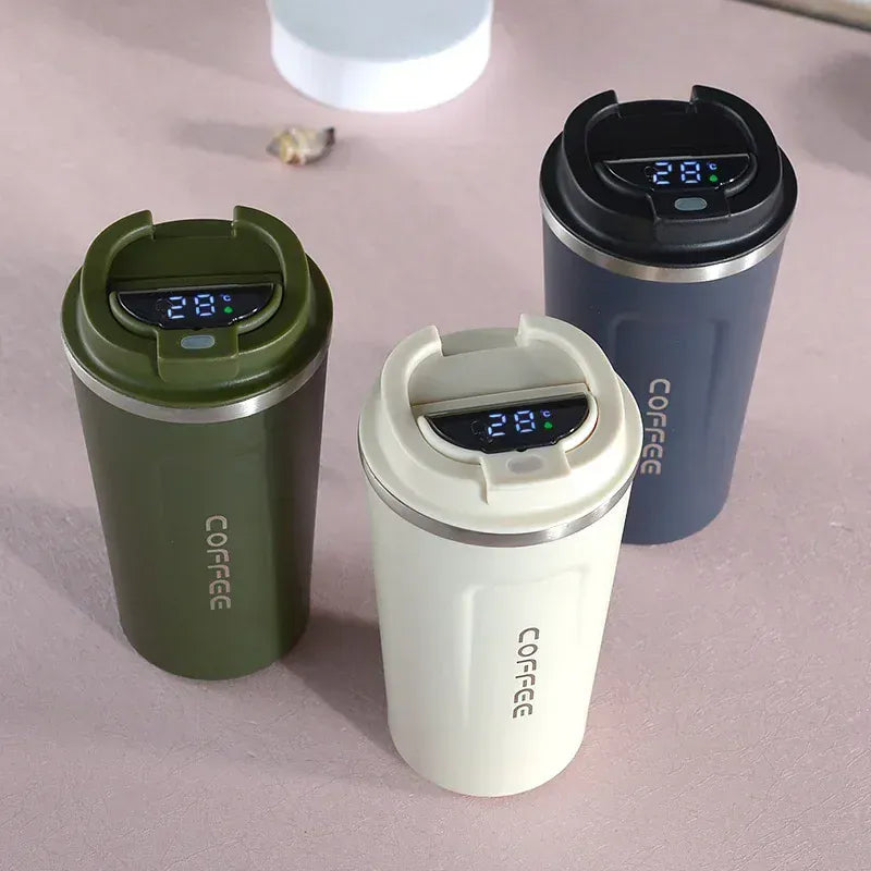 Three insulated coffee cups with digital temperature displays on a pink surface.