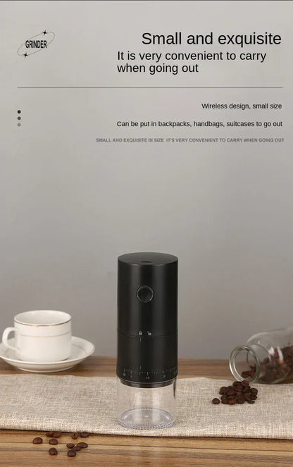 Black coffee grinder on a wooden surface with coffee beans and a cup, against a gray background.