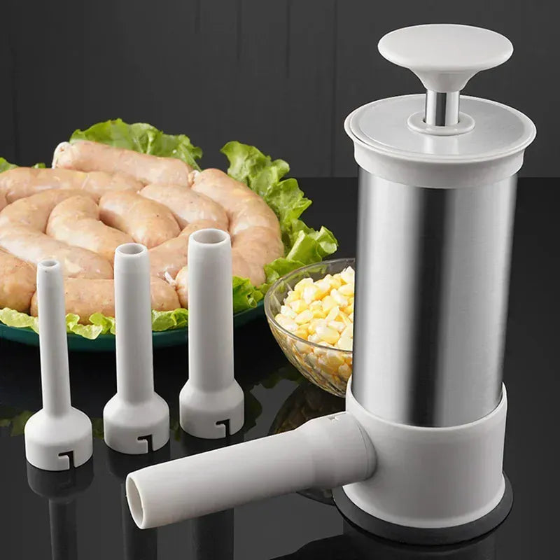 Marinade injector with interchangeable nozzles on a dark surface with raw chicken and corn in the background.